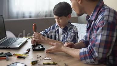关爱的父亲教他的小儿子在家修理硬盘驱动器，爱好